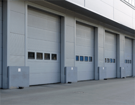 A commercial building with four large white garage doors