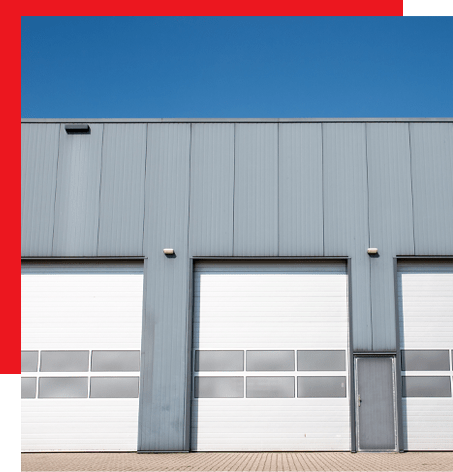 A gray commercial buiding with three white garage doors