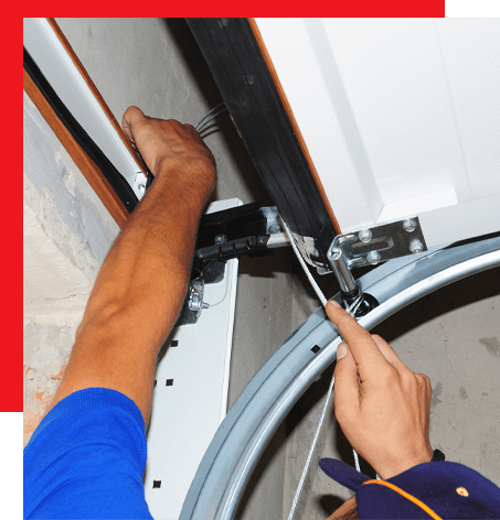 A close-up of a workers' hand repairing a garage door mechanism